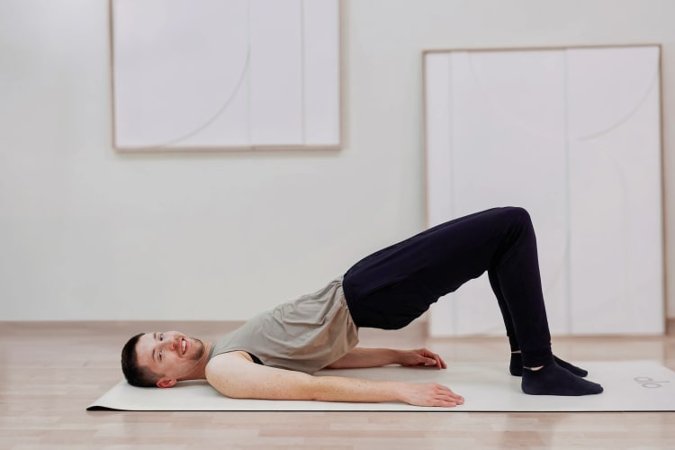 Eine Person macht die Pilates Übung Schulterbrücke.