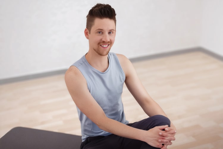 Ein Mann sitzt in Sportkleidung und lacht