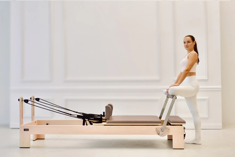 Eine Trainerin macht eine Dehnübung auf dem Reformer.
