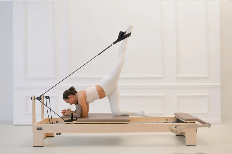 Eine Trainerin macht eine Dehnübung auf dem Reformer.