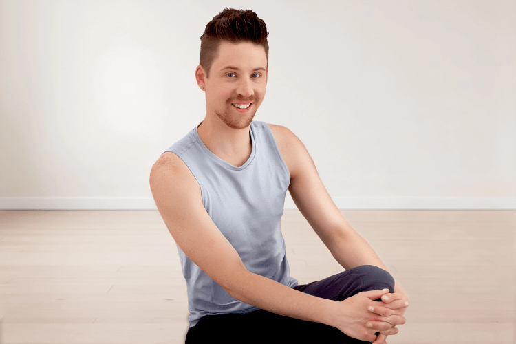 Trainer Fabian sitzt lächelnd auf der Pilates Matte im Pilates Men Kurs