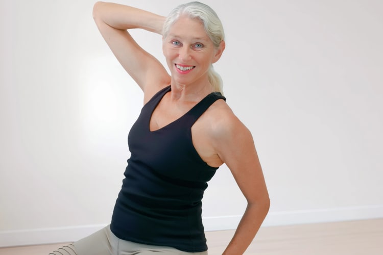 Eine Frau macht Pilates Schulter-Nacken Übungen im Sitzen