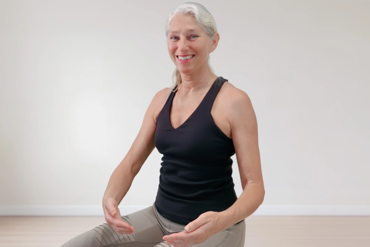 Eine Frau macht Pilates Übungen für die Arme im Sitzen