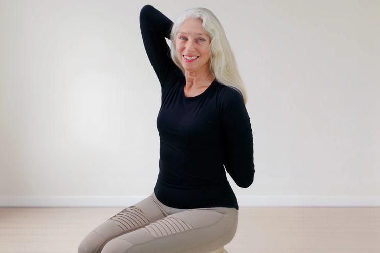 Eine Frau macht Pilates Übungen für die Arme im Sitzen