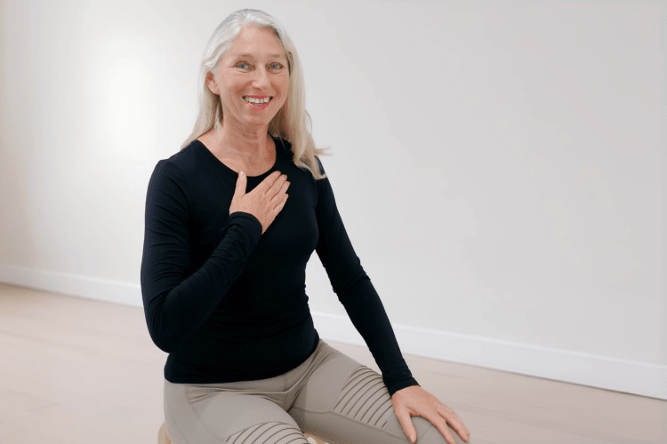Eine Frau trainiert die Pilates Atmung im Sitzen