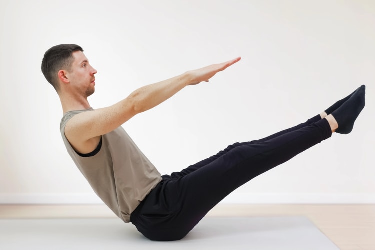 Eine Person macht die Pilates Übung Teaser.