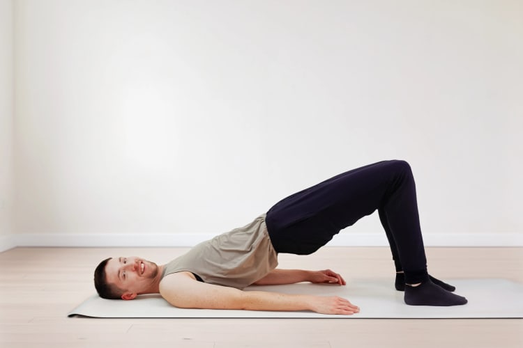 Eine Person macht die Pilates Übung Schulterbrücke.