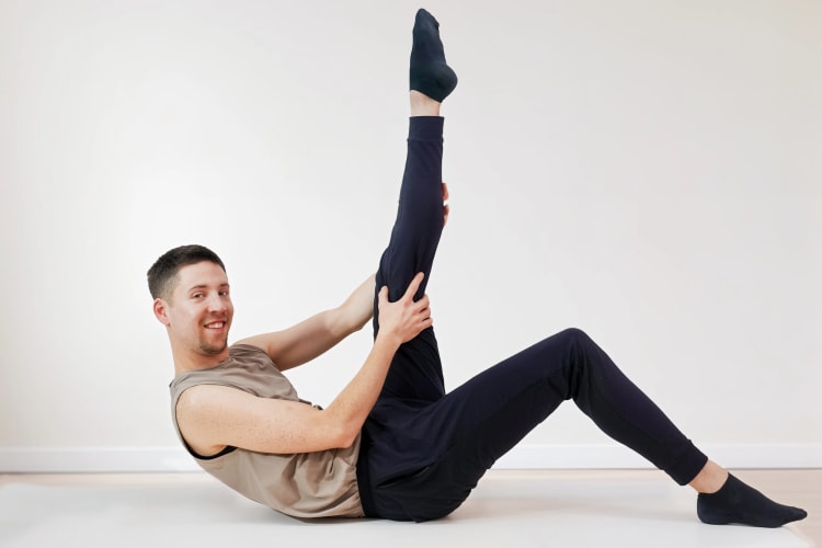 Eine Person macht eine Dehnungs Pilates Übung.