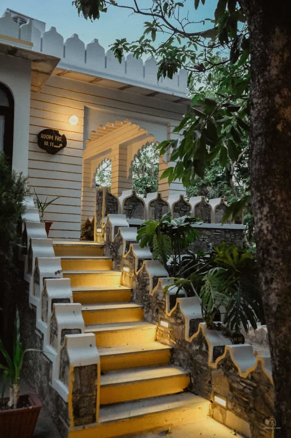 Illuminated steps beneath leafy arches at The Aodhi