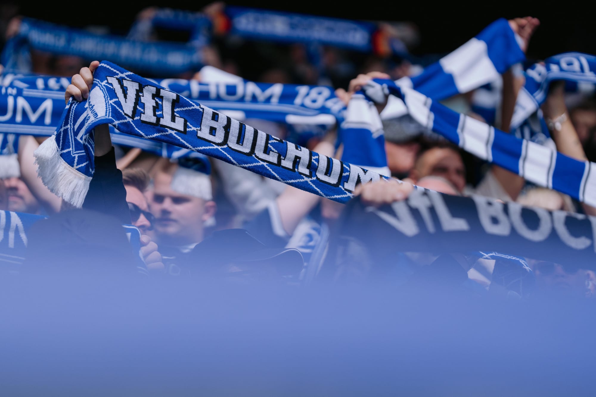 Fans im Stadion halten ihre Schals hoch