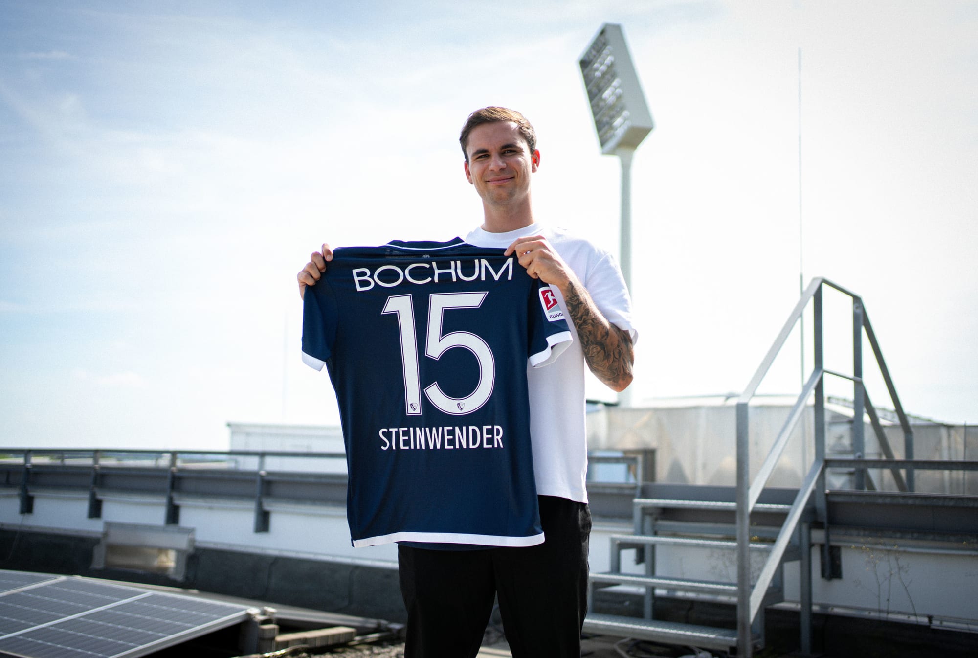 Neuzugang Michael Steinwender hält das Trikot mit seiner Nummer 15 hoch.