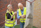 Preventiemedewerkers in gele hesjes inspecteren het speeltoestel op het schoolplein