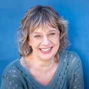 lachende vrouw achter felblauwe muur