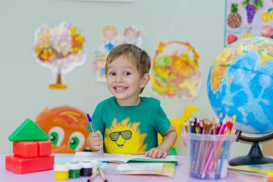 vrolijk kind in klaslokaal met trui met zonnetje