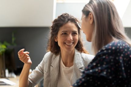 een vriendelijk lachende vrouw coacht een schoolleider
