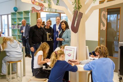 staatssecretaris paul kijkt naar werkende leerlingen samen met denis vijgen, directeur vfpf en geke faber, vorozitter van bestuur