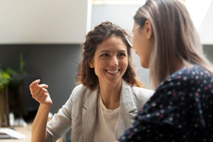 een vriendelijk lachende vrouw coacht een schoolleider