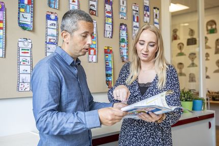 leerkracht en mentor in klaslokaal wijzend naar een boek