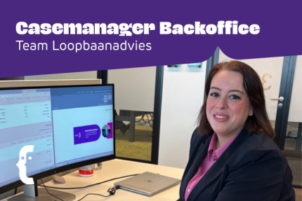 Vrouwelijke casemanager kijkt in camera, achter 2 laptop schermen