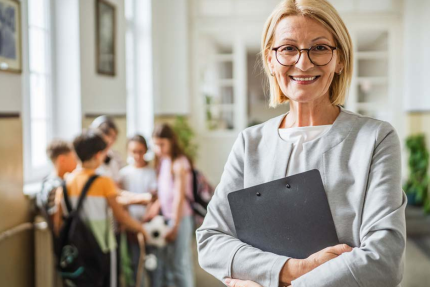 mevrouw ouder dan 50 jaar met map onder de arm in schoolgebouw