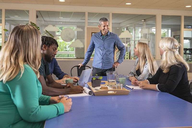 Schoolleider in gesprek met leerkrachten over hun werkgeluk