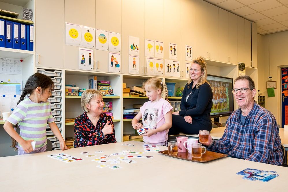 klaslokaal met kinderen, schooldirecteur Angela Maas, onderwijsassistenten Pim en concierge Frans