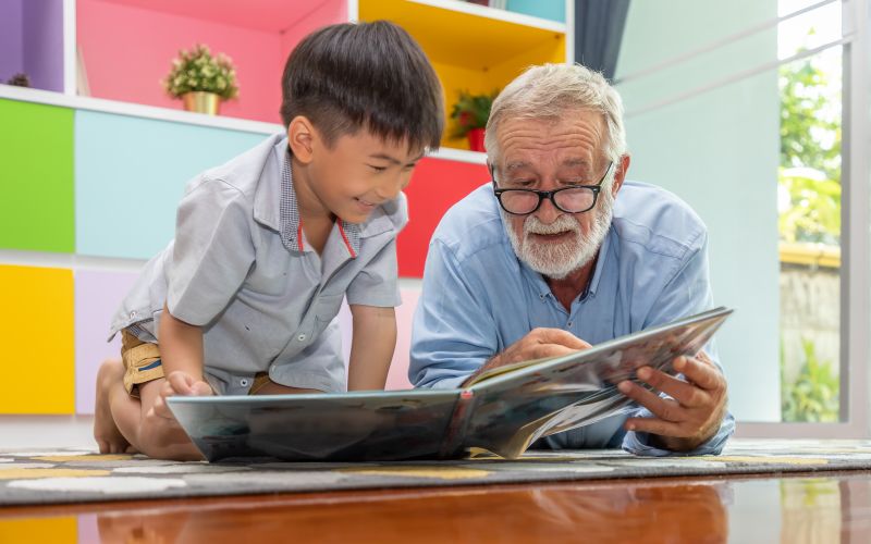 Oudere leerkracht leest jongen voor uit een boek