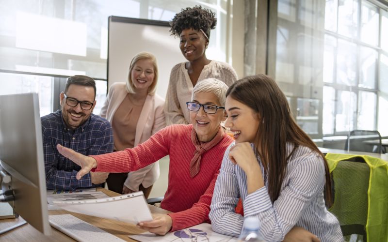 Verschillende generaties achter een computer die met elkaar bespreken wat er op de computer gebeurt