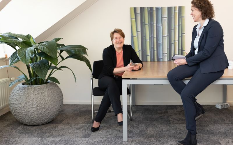 2 vrouwen in kamer met plant in kantoorsetting