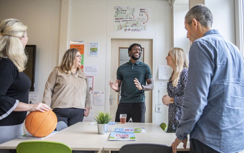 Groepje leerkrachten staand bij een tafel in overleg