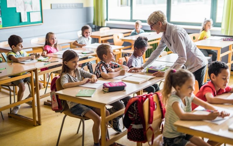 Oudere leerkracht in een klas vol kinderen 