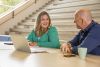 Een juf en haar leidinggevende zijn in gesprek. Laptop staat voor hen open op tafel.