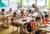 Oudere leerkracht in een klas vol kinderen 