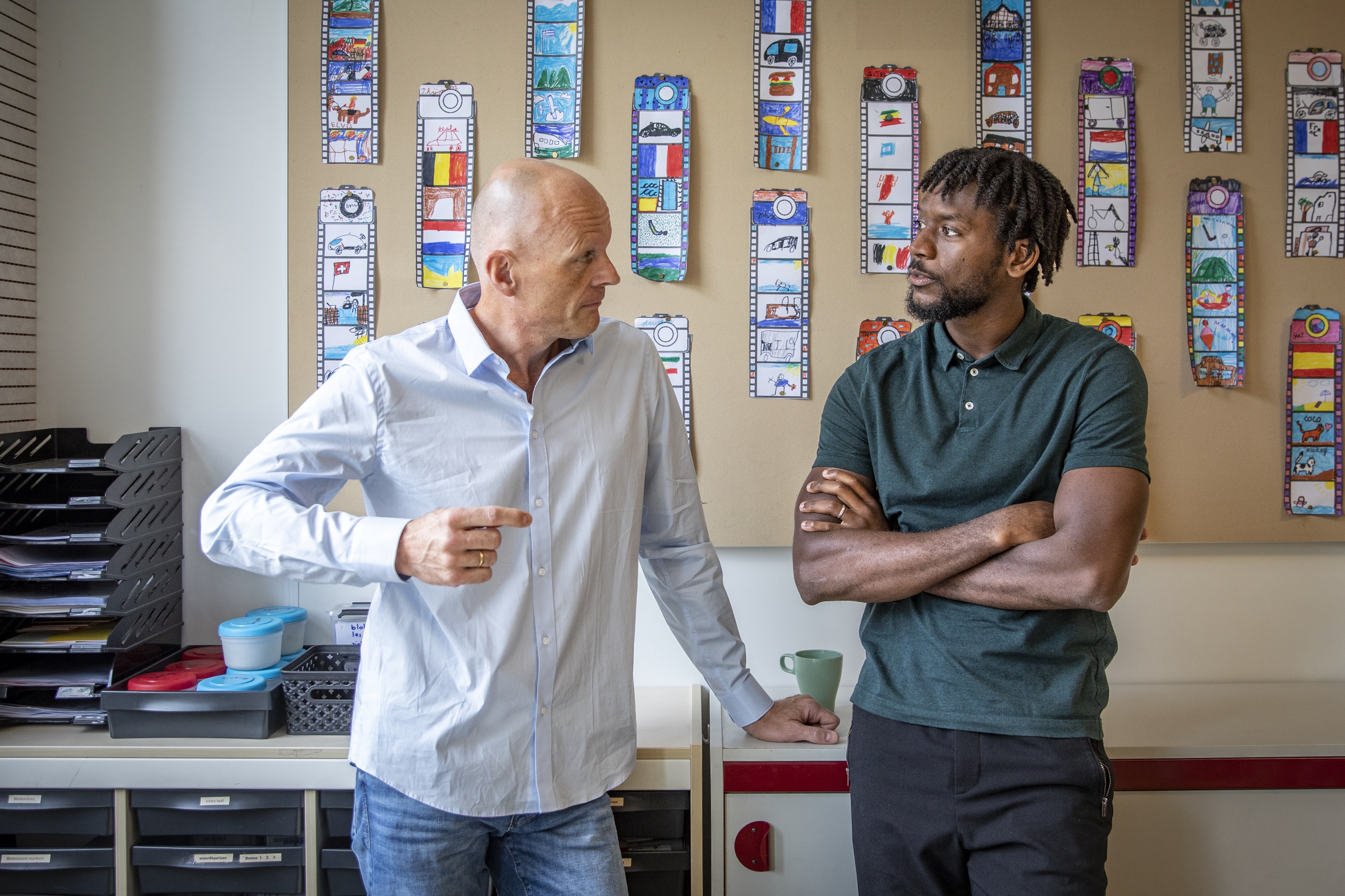 directeur en jonge leerkracht staand in gesprek in klaslokaal