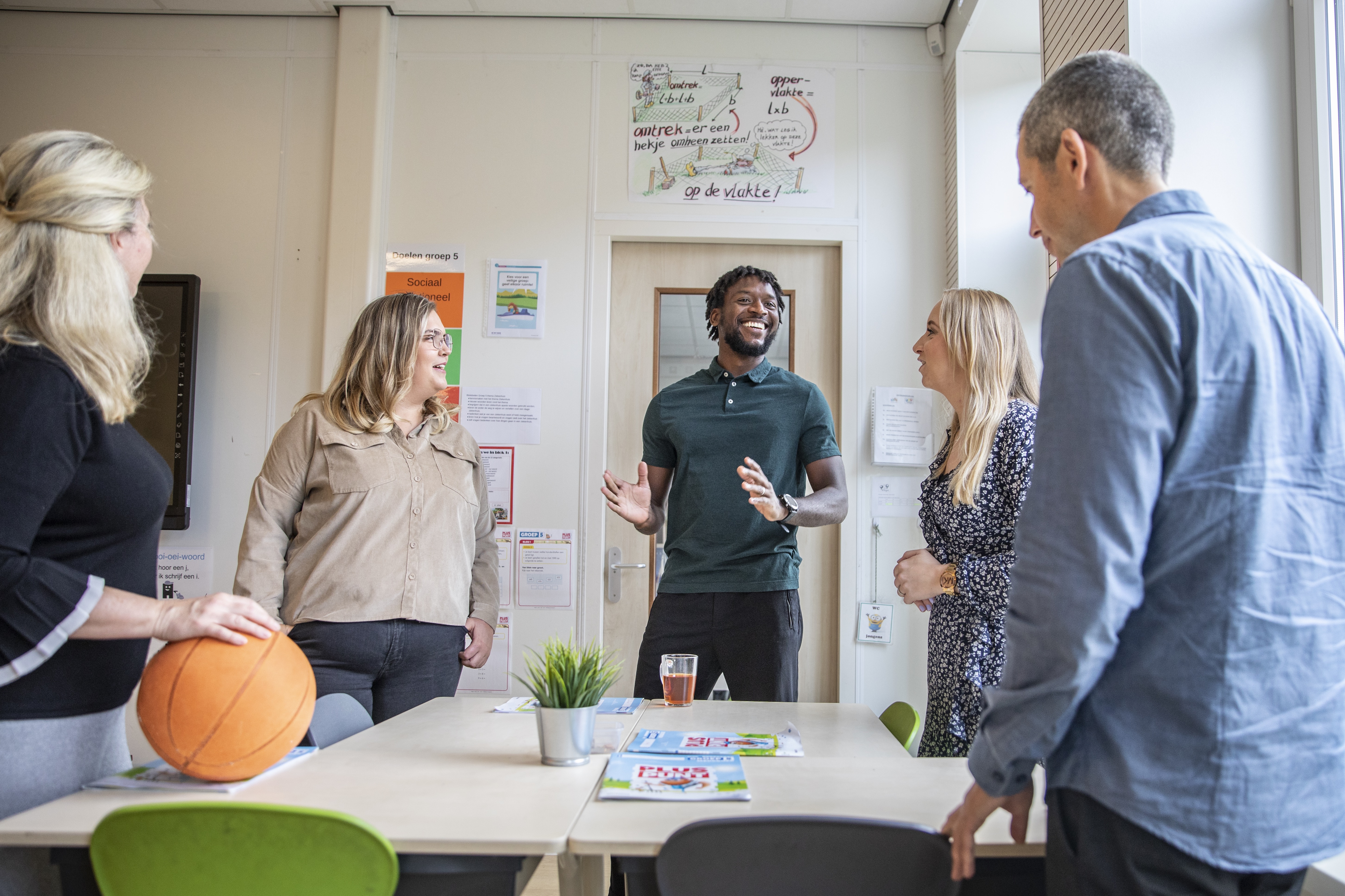 groepje leerkrachten staand bij een tafel in overleg