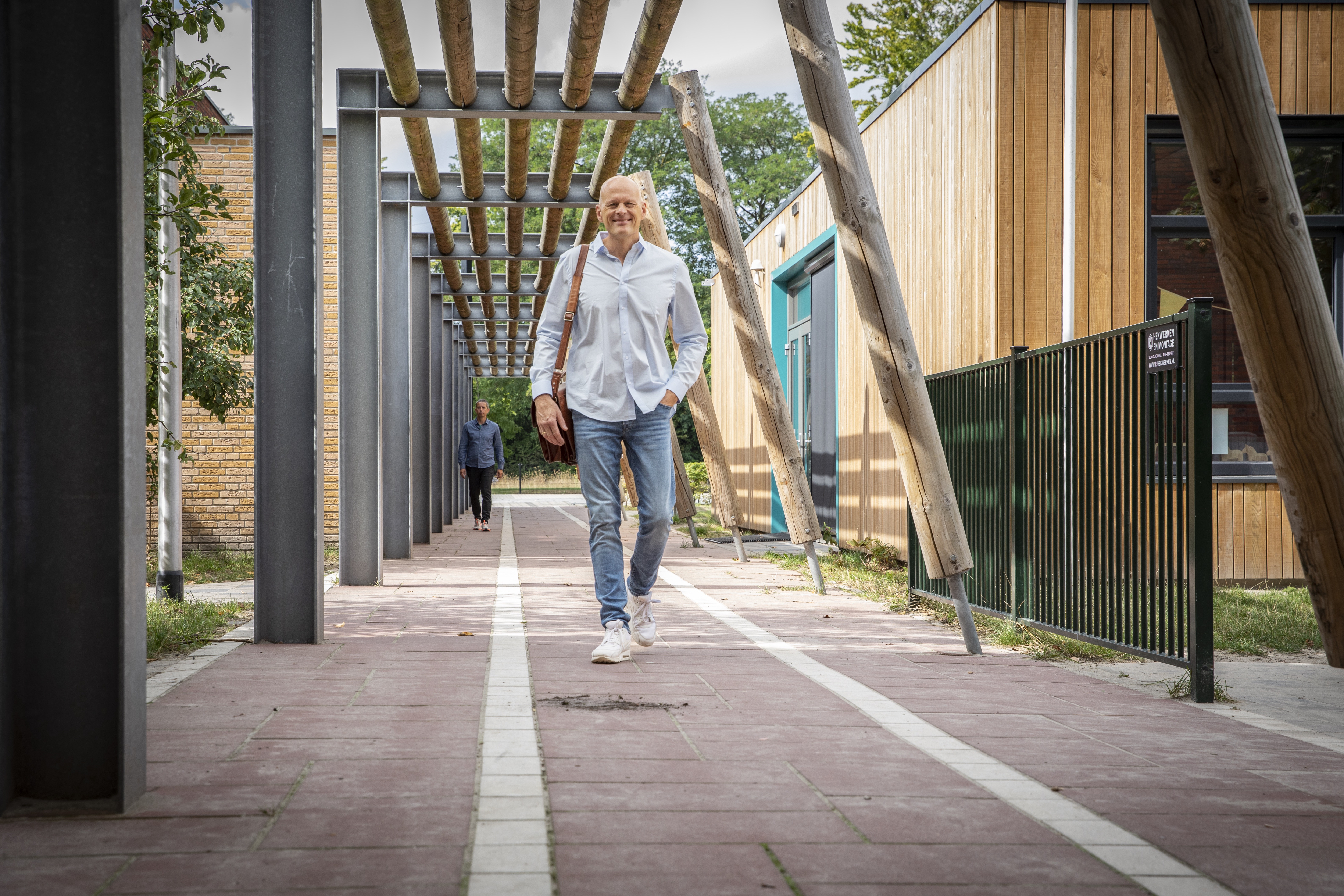 portret schooldirecteur wandelend richting ingang school