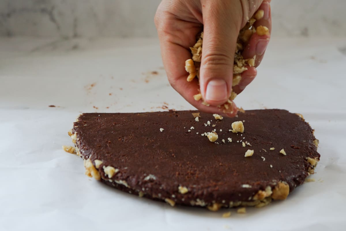 sprinkling walnuts on folded brownies mixture