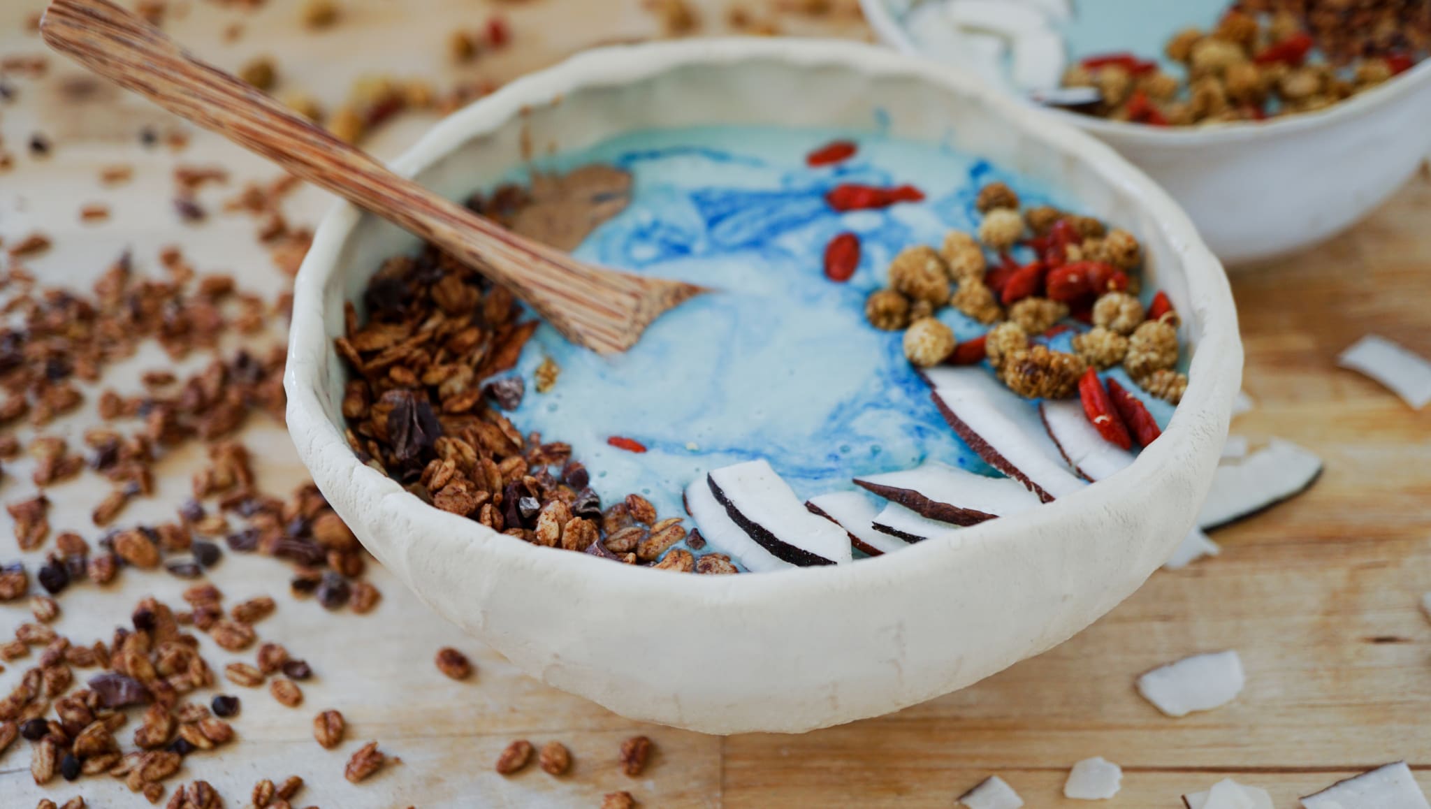 blue majik spirulina smoothie bowl with toppings and a wooden spoon