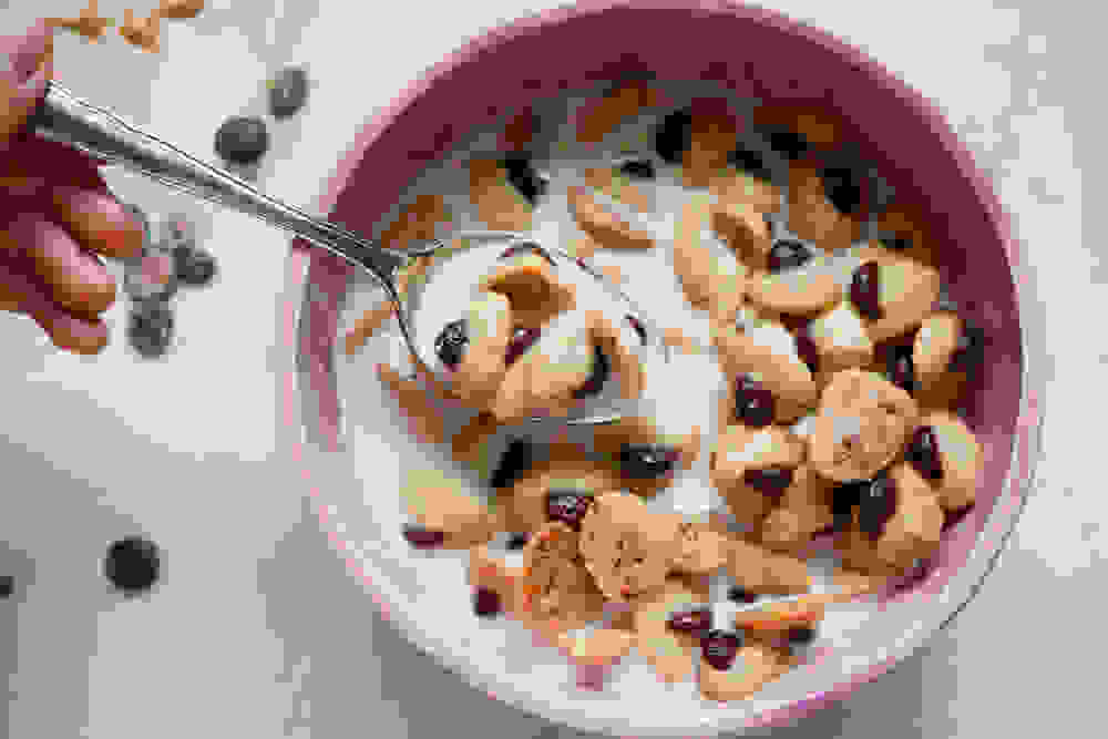 a spoon of mini vegan peanut butter chocolate hamantaschen cereal with almond milk