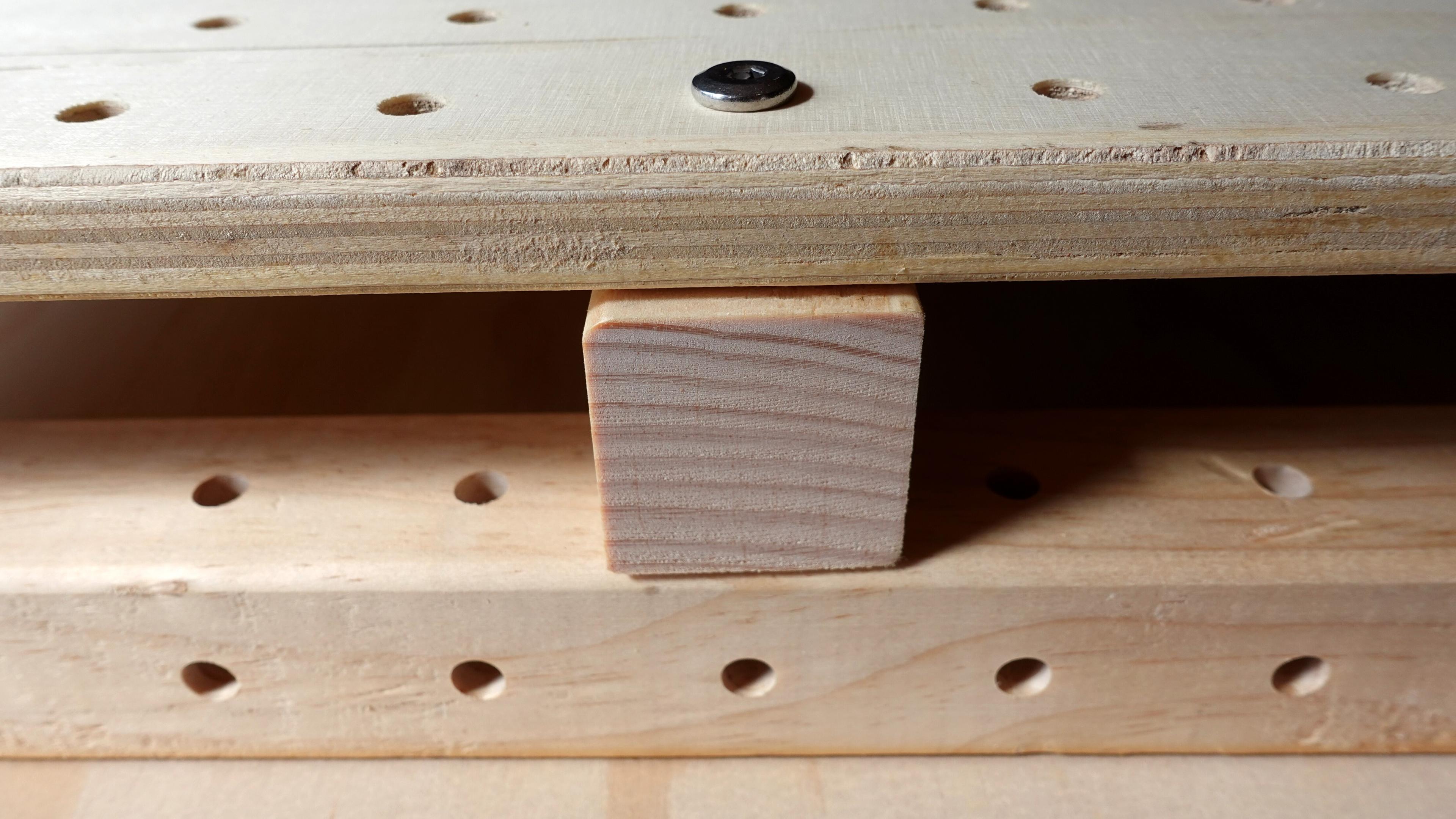 Two wooden beams are joined by a bolt passing through a 18mm panel, with a second beam visible beneath the panel, creating a stacked connection.