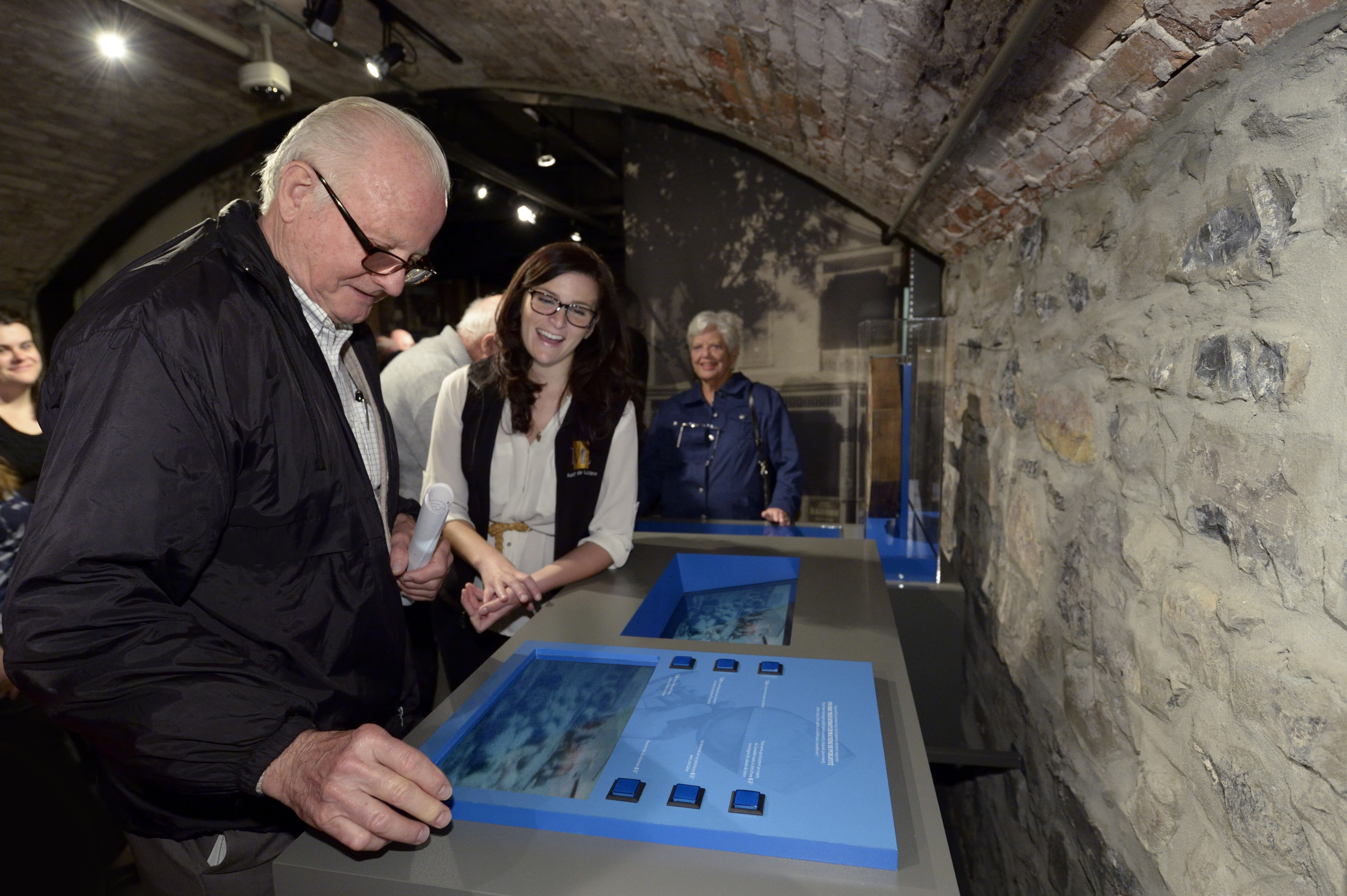 Homme devant une vitrine de mus&eacute;e accompagn&eacute; d'une guide