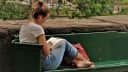 Femme assise sur un banc de parc avec un livre.