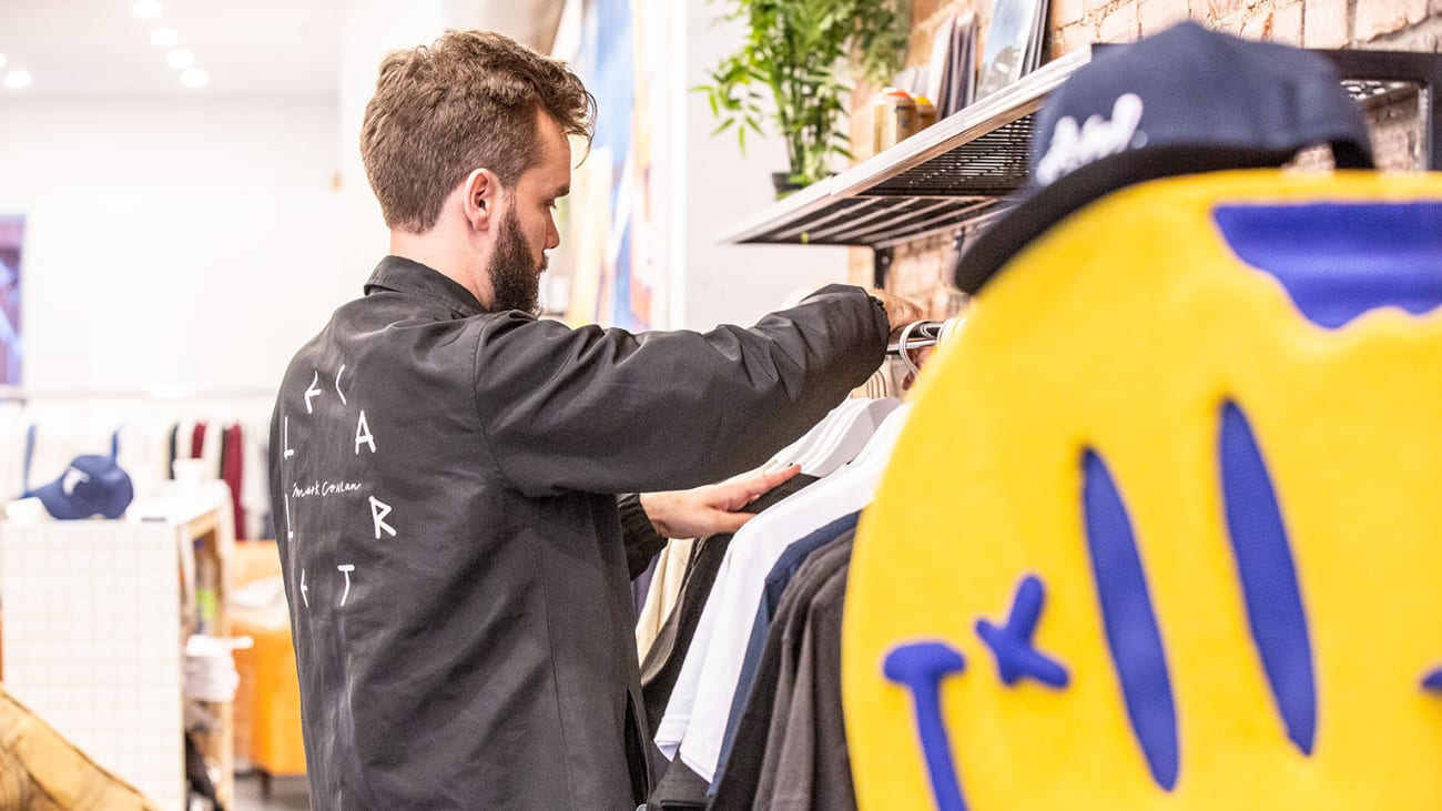 Un employé place des vêtements dans une boutique