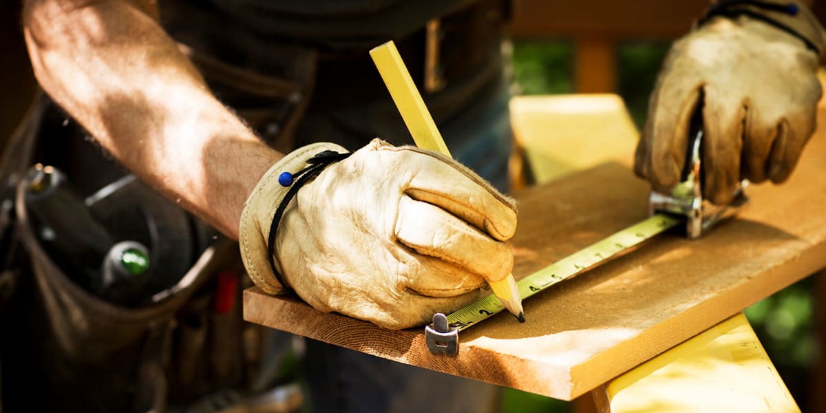 Un homme travaille et prend des mesures sur une planche de bois à l'extérieur de sa maison. Un homme travaille et prend des mesures sur une planche de bois à l'extérieur de sa maison.