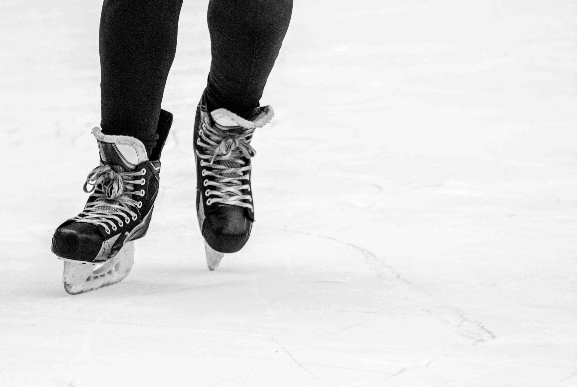photo de deux pieds chaussés de patins noirs sur la glace extérieure