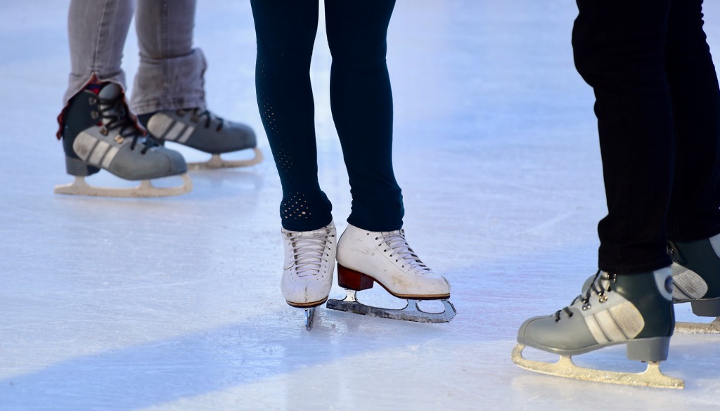 Les jambes de trois patineurs sur une surface glacée.