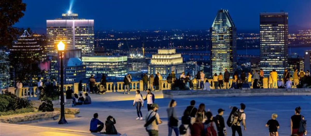 Personnes sur le belvédère du mont Royal en soirée avec vue sur la ville
