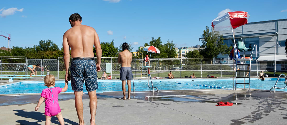 Un homme et son enfant près de la piscine du parc Jarry