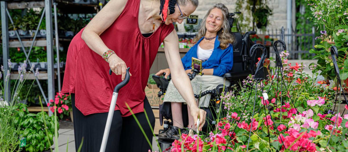 Dame en fauteuil roulant et dame avec canne magasinant des fleurs
