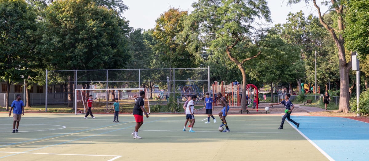 Jeunes qui jouent au soccer sur le terrain multisport du parc